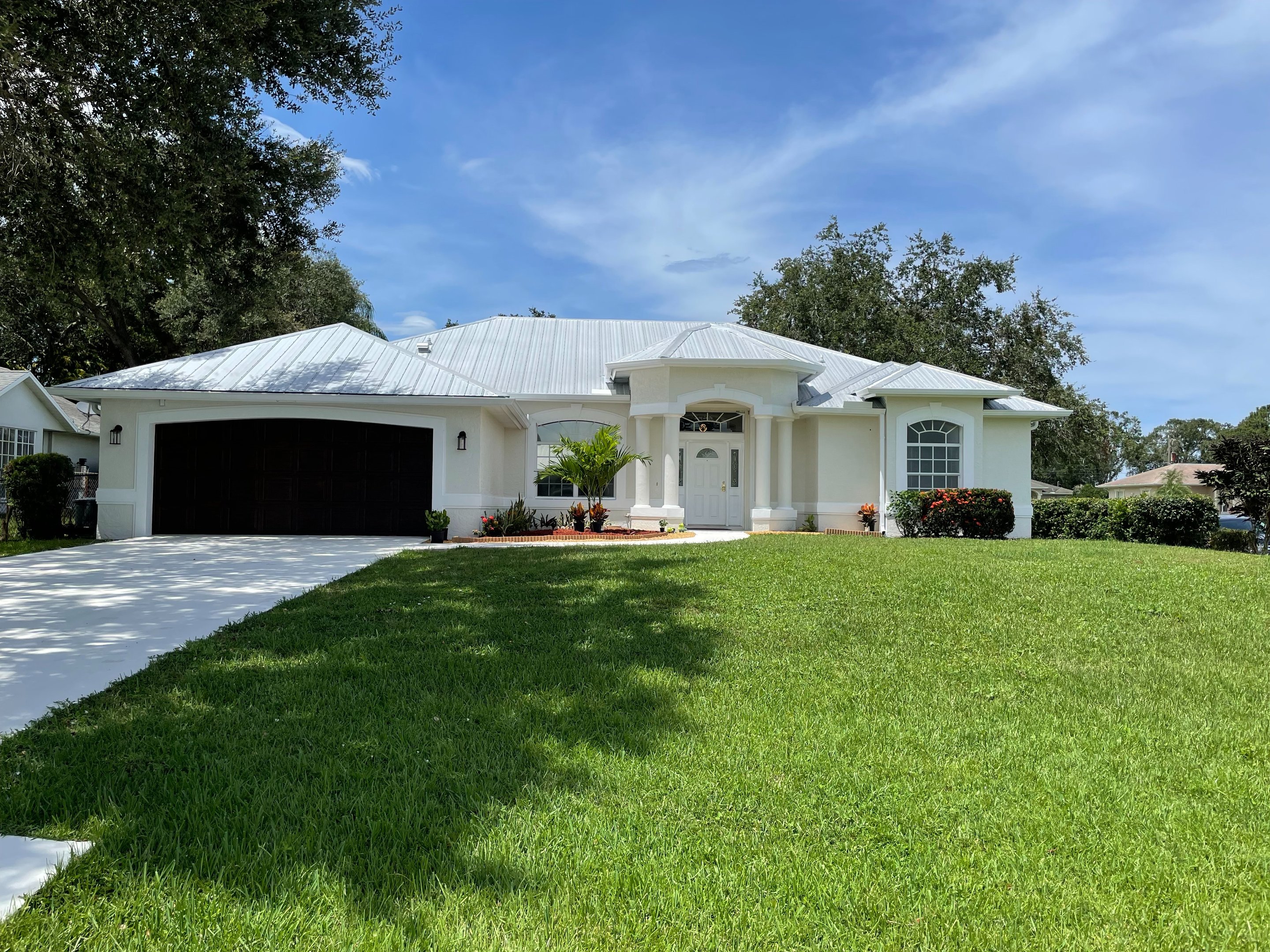 Exterior repaint of a white Florida home with fresh trim and garage door