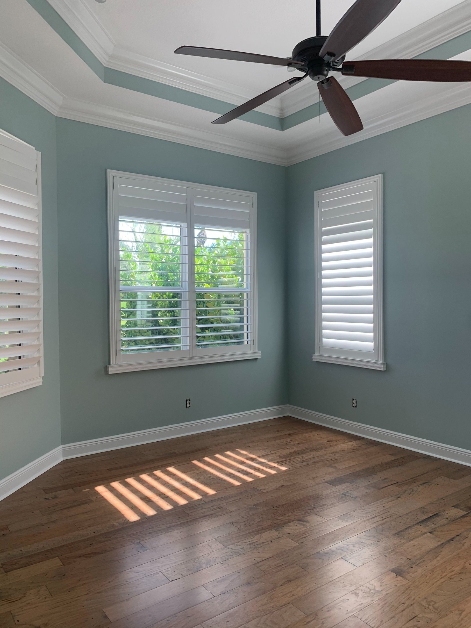 Interior bedroom painted in soft coastal sage with white trim and tray ceiling in Stuart FL